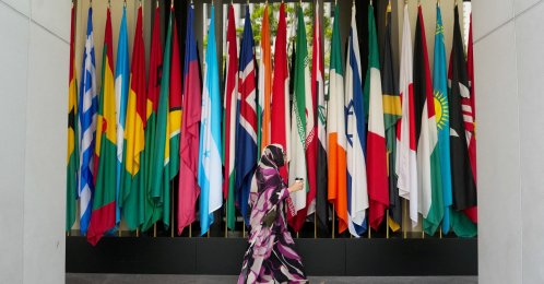 A woman walks by a long row of flags at the IMF building during the 2026 annual IMF-World Bank Spring Meetings, Washington, D.C., U.S., April 16, 2026. (Reuters Photo)
