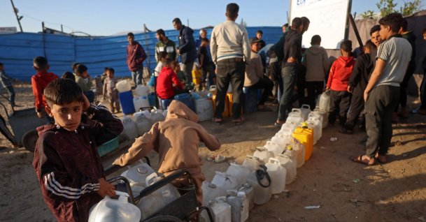 People and children stand next to their containers while waiting to fetch drinking water at a makeshift camp for displaced Palestinians in Khan Yunis, in the southern Gaza Strip, April 10, 2026. (AFP Photo)