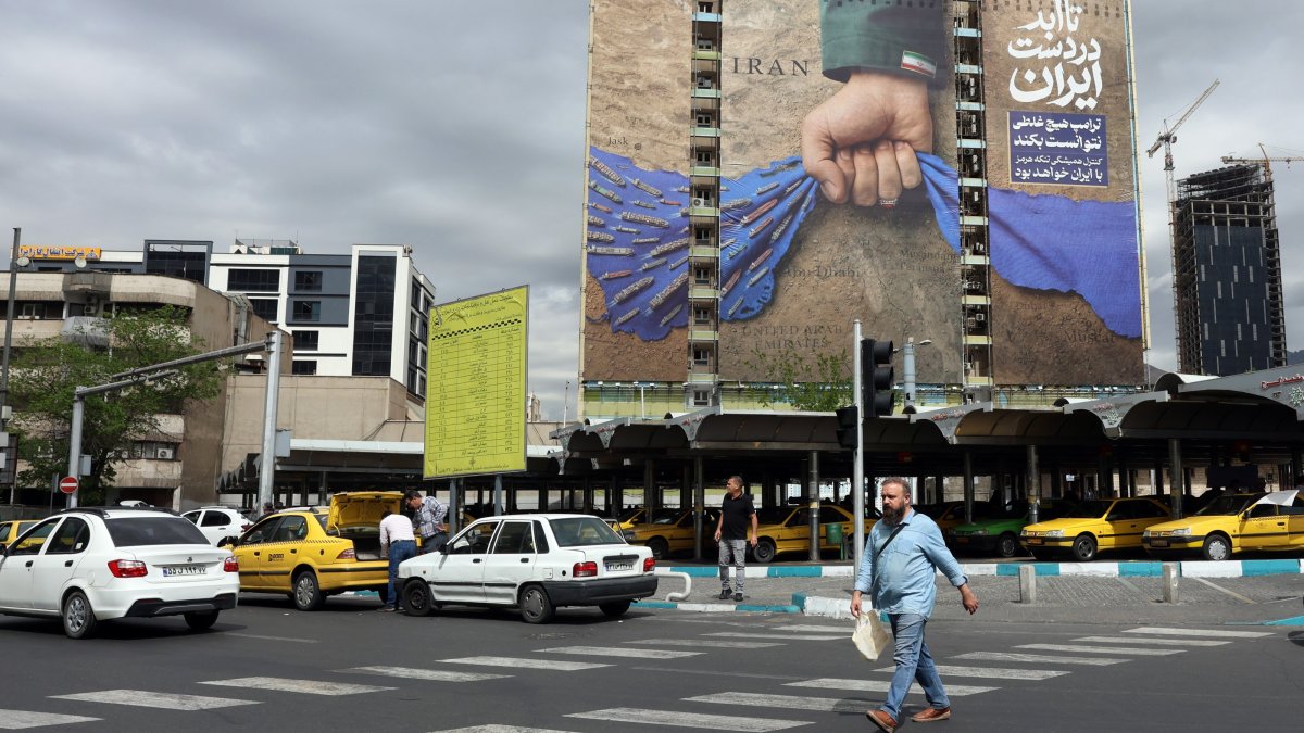 Iranians walk past a large-scale billboard referring to the Strait of Hormuz and reading in Persian, "Forever in Iran’s hand,” in a square in Tehran, Iran, April 19, 2026. (EPA Photo)