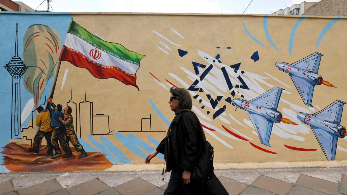 A woman walks past an anti-U.S. and anti-Israel mural in Tehran, Iran, April 21, 2026. (AFP Photo)