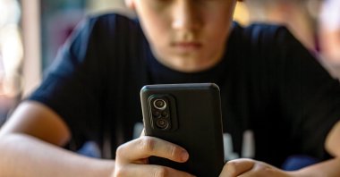 A teenager uses a smartphone, illustrating concerns about digital media use among young people. (Shutterstock Photo)