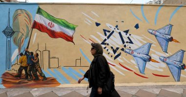 A woman walks past an anti-U.S. and anti-Israel mural in Tehran, Iran, April 21, 2026. (AFP Photo)