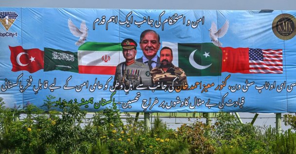 Motorcyclists ride past a billboard featuring Pakistan's Prime Minister Shehbaz Sharif (C) and Army Chief and Field Marshal Syed Asim Munir (L) ahead of anticipated U.S.-Iran peace talks, in Islamabad, Iran, April 20, 2026. (AFP Photo)