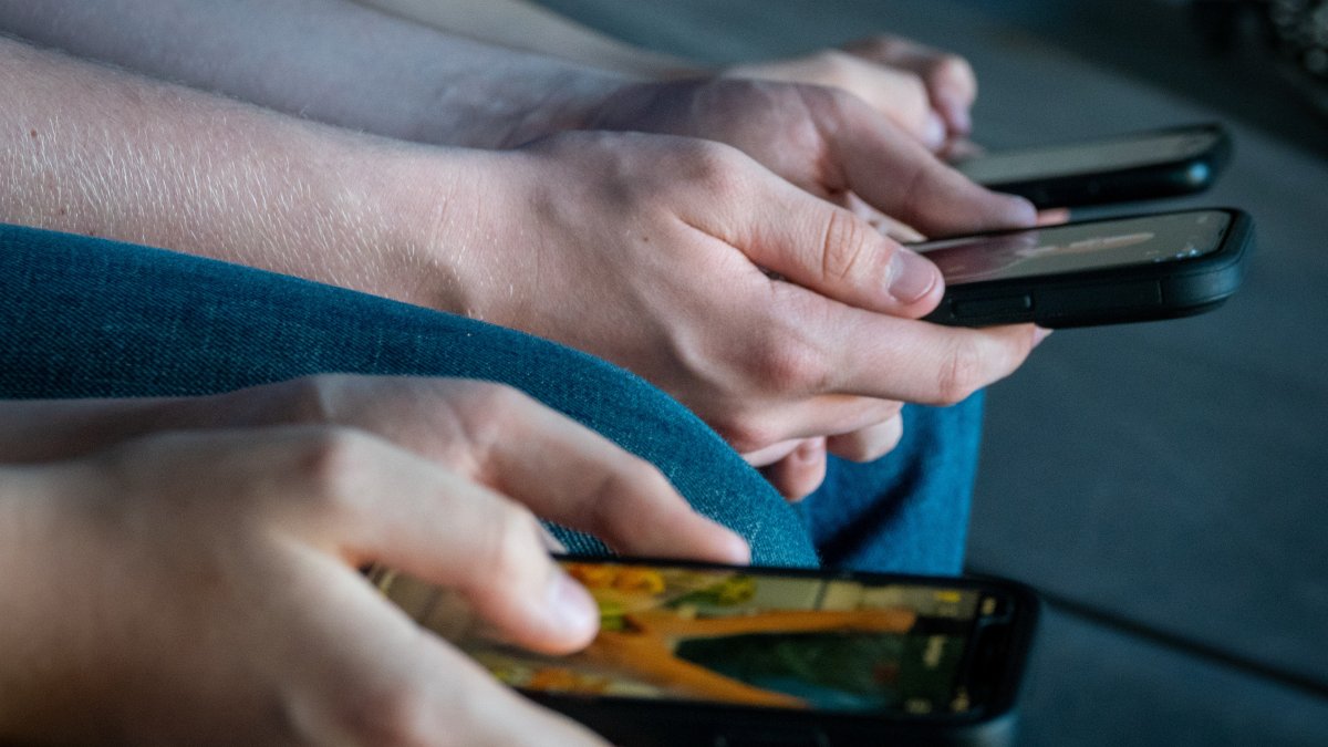 Three teenage boys looks at their smartphone screens, Morzine, France, April 11, 2025. (Getty Images Photo)