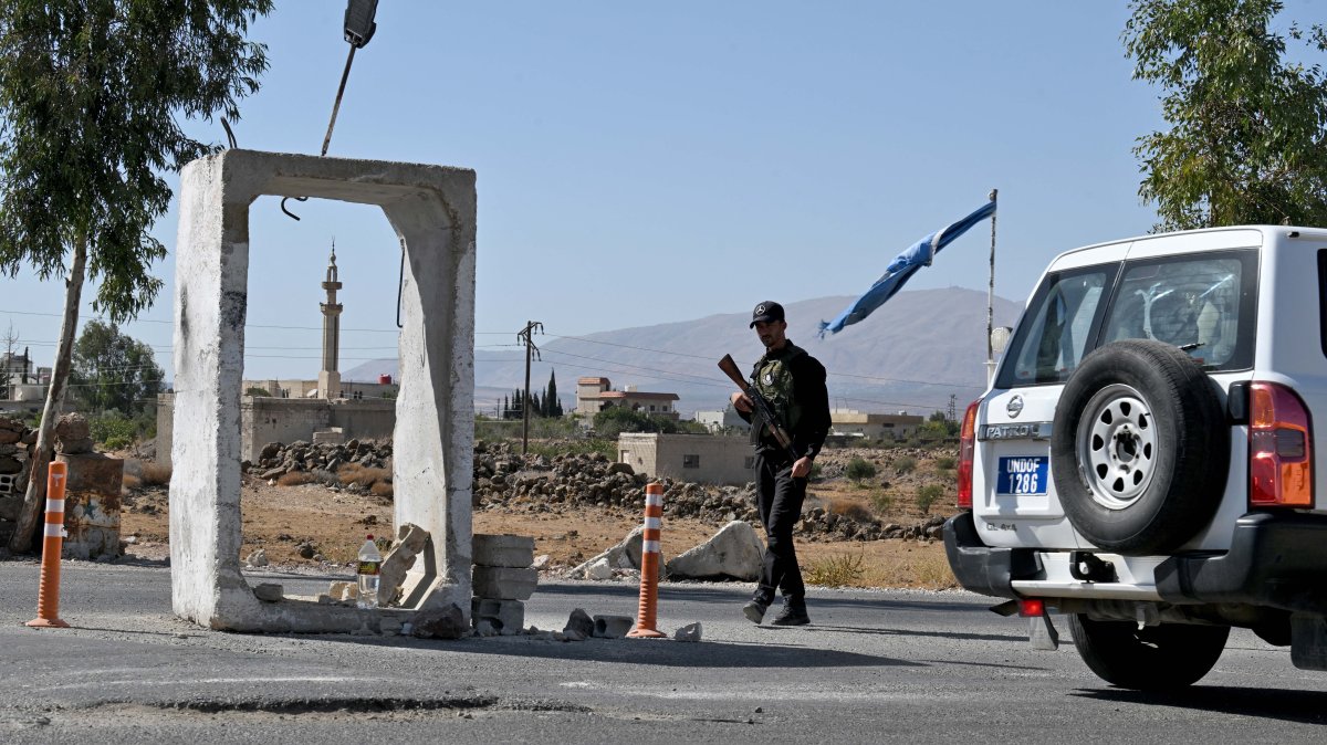A United Nations Disengagement Observatory Force (UNDOF) vehicle drives past a member of Syria's security forces standing guard outside a former army base near the city of Quneitra in southern Syria, on the edge of the Israeli-occupied Golan Heights, Sept. 21, 2025. (AFP File Photo)