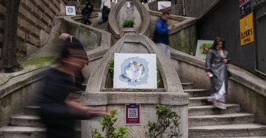 People walk past portraits designed by Ruken Adıbelli displayed on stairs, Istanbul, Türkiye, April 9, 2026. (AA Photo)