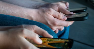 Three teenage boys looks at their smartphone screens, Morzine, France, April 11, 2025. (Getty Images Photo)
