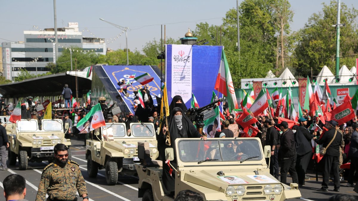 Women march in support of the government during a rally marking National Army Day, with participants carrying weapons and moving alongside military vehicles, Tehran, Iran, April 17, 2026. (AA Photo) 