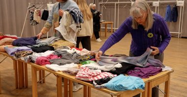 Meg Goldmann (R), a volunteer with the Swedish Society for Nature Conservation, folds secondhand clothes at a clothing swap event, Stockholm, Sweden, April 19, 2026. (AP Photo)