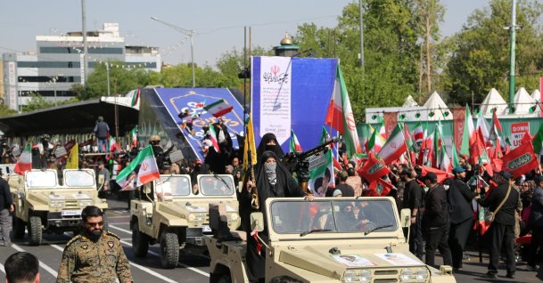 Women march in support of the government during a rally marking National Army Day, with participants carrying weapons and moving alongside military vehicles, Tehran, Iran, April 17, 2026. (AA Photo) 