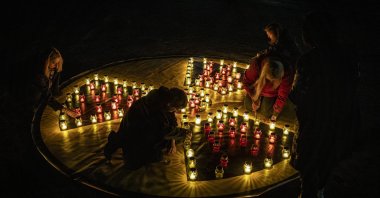 Ukrainians light candles arranged in the shape of a radiation symbol near a memorial for liquidators who died during cleanup operations after the Chernobyl nuclear power plant disaster, during a ceremony in Slavutich, Ukraine, April 26, 2026. (EPA Photo)
