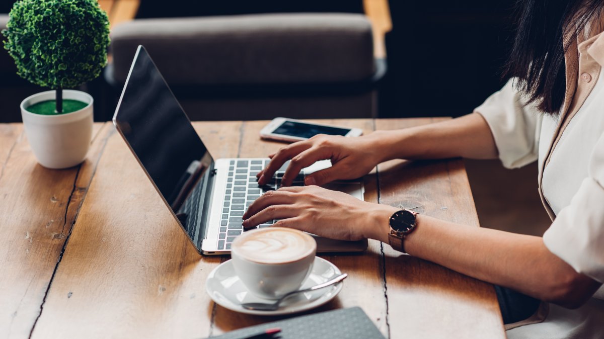 A working woman using her laptop in a cafe with a coffee. (Shutterstock Photo)
