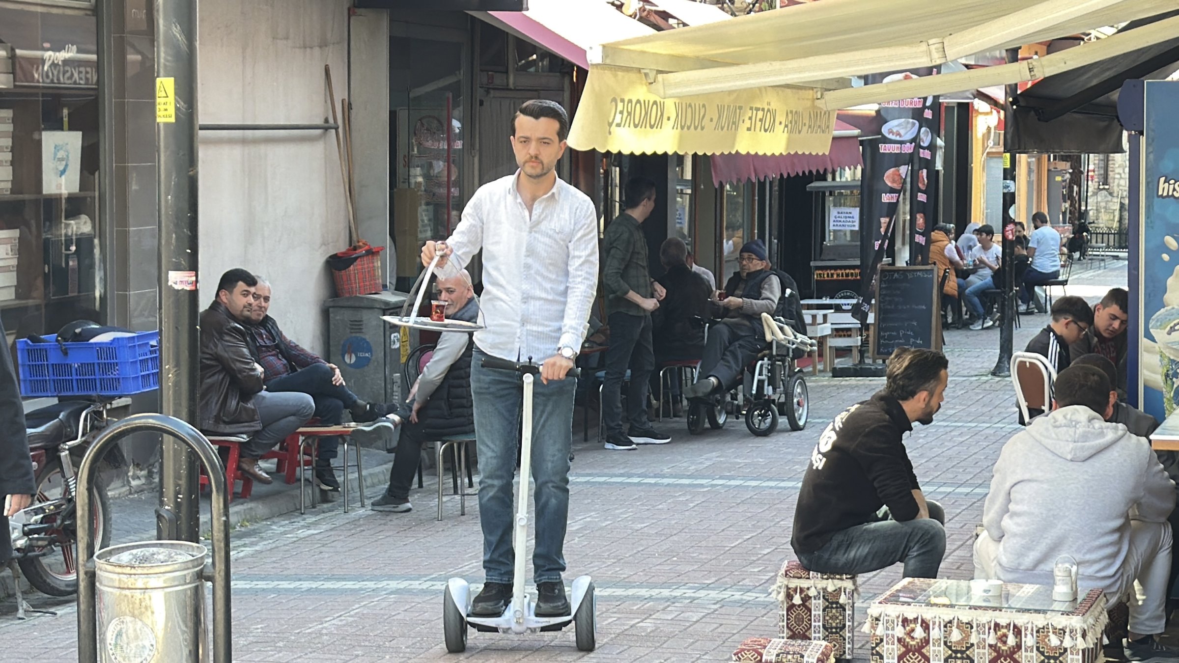 Basri Akbıyık delivers tea on a hoverboard while balancing a tray along a street, Bartın, Türkiye, April 26, 2026. (DHA Photo)