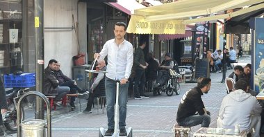 Basri Akbıyık delivers tea on a hoverboard while balancing a tray along a street, Bartın, Türkiye, April 26, 2026. (DHA Photo)