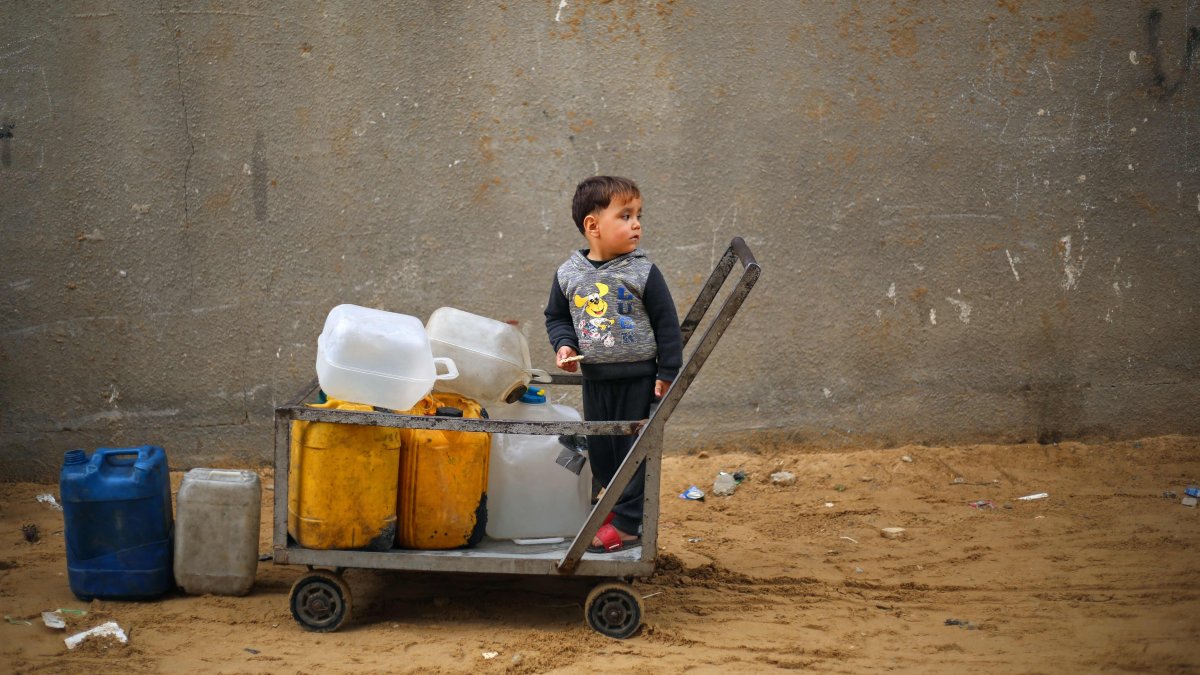 A displaced Palestinian boy stands on a trolley loaded with empty water canisters at the Nuseirat refugee camp, central Gaza Strip, Palestine, April 1, 2026. (AFP Photo)