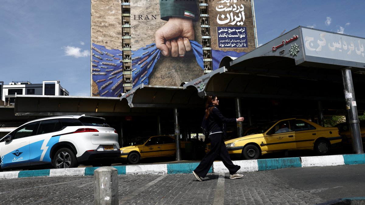 A woman walks past a billboard with a graphic design about the Strait of Hormuz on a building, in Tehran, Iran, April 27, 2026. (Reuters Photo)