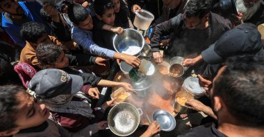 Displaced Palestinians receive food from a charity kitchen at the Nuseirat refugee camp in the central Gaza Strip on April 22, 2026. (AFP Photo)