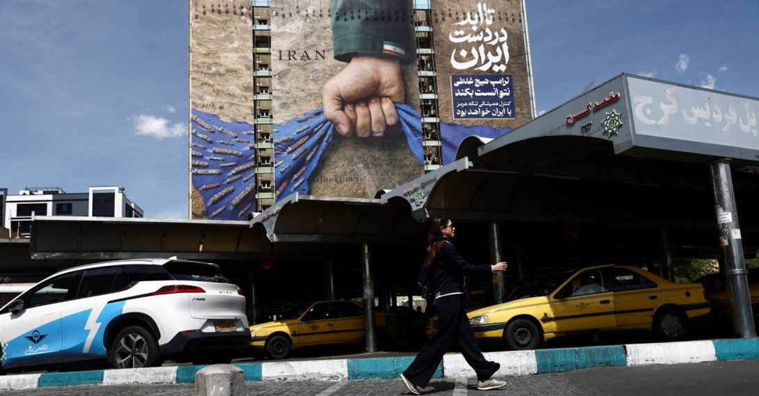 A woman walks past a billboard with a graphic design about the Strait of Hormuz on a building, in Tehran, Iran, April 27, 2026. (Reuters Photo)