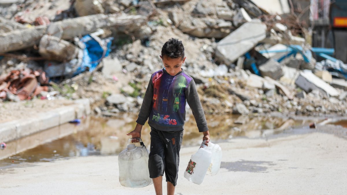 A Palestinian child carries water in a container after filling it from a tanker in Bureij Camp, Gaza, Palestine, April 28, 2026. (AA Photo) 