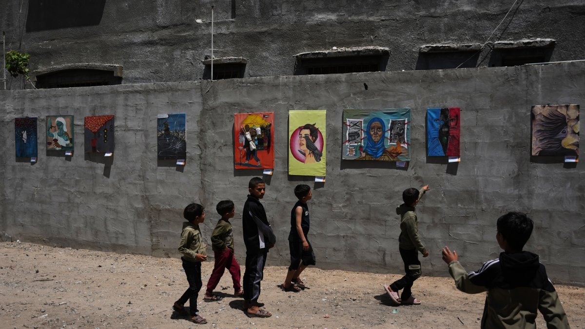 Children look at paintings by Palestinian artists during an exhibition in al-Bureij camp in the central Gaza Strip, Palestine, April 28, 2026. (AP Photo)