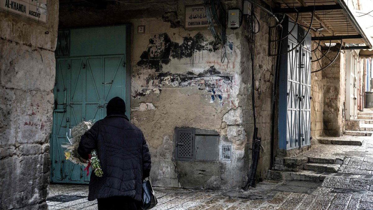 An Orthodox Christian nun walks with a bouquet of flowers through a deserted alley in the Christian Quarter in the old city of Jerusalem, April 3, 2026. (AFP File Photo)