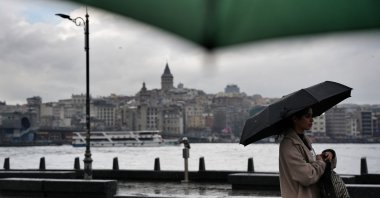 A person is seen walking with a backdrop of Galata Tower, Istanbul, Türkiye, April 10, 2026. (IHA Photo)