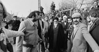 Followers form a human chain around the Ayatollah Ruhollah Khomeini, to protect him from the crowd massed as he walks back to his residence a few hours before leaving for Charles de Gaulle Airport where he is scheduled to fly to Tehran after more than 14 years in exile, in suburban Neauphle-le-Chateau, outside Paris, France, Jan. 31, 1979. (AP Photo)
