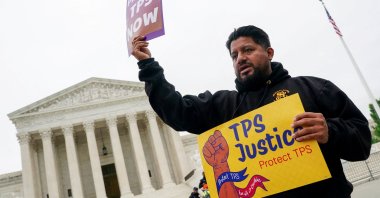 A man holds placards as immigrants' rights activists and demonstrators attend a rally outside the U.S. Supreme Court, as justices hear arguments on whether the administration of U.S. President Donald Trump can end the Temporary Protected Status (TPS) of Syrian and Haitian nationals, in Washington, D.C., U.S., April 29, 2026. (Reuters Photo)