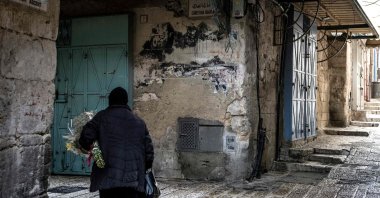 An Orthodox Christian nun walks with a bouquet of flowers through a deserted alley in the Christian Quarter in the old city of Jerusalem, April 3, 2026. (AFP File Photo)
