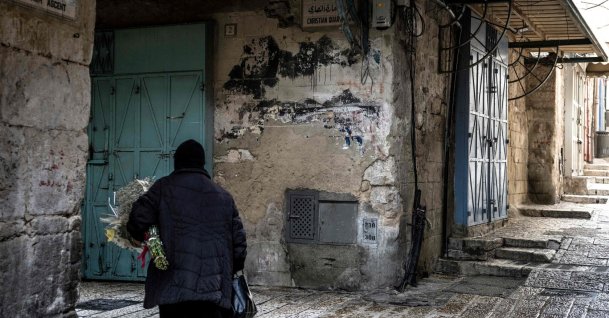 An Orthodox Christian nun walks with a bouquet of flowers through a deserted alley in the Christian Quarter in the old city of Jerusalem, April 3, 2026. (AFP File Photo)