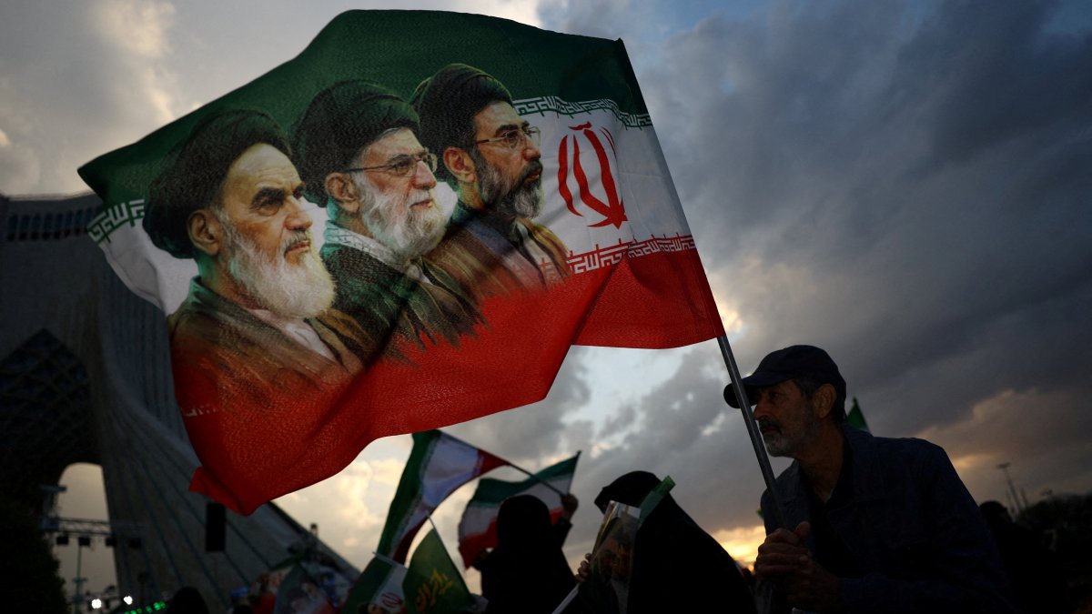 A man holds a flag with a picture of late leader of the Islamic Revolution Ayatollah Ruhollah Khomeini, late Supreme Leader of Iran Ayatollah Ali Khamenei and Iran's new Supreme Leader Mojtaba Khamenei, during a rally in Tehran, Iran, April 29, 2026. (Reuters Photo)