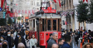 A red nostalgic tram passes by the crowded Istiklal Street in the Beyoğlu district, Istanbul, Türkiye, Dec. 3, 2021. (Getty Images Photo)