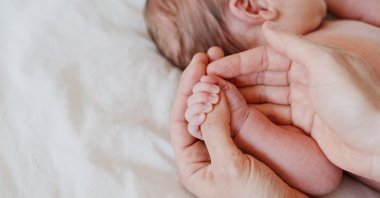 Close-up little hand of child baby holding hand of mother. (Shutterstock Photo)