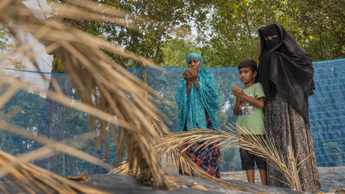 Shahida Khatun (L), mother, Mahadi (C), son, and Sadia Islam Sarmin, wife of Mohammad Abdullah Al Mamun, pray beside Mamun's grave in Rasulpur village, Mymensingh district, Bangladesh, April 17, 2026. (AP Photo)