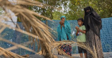 Shahida Khatun (L), mother, Mahadi (C), son, and Sadia Islam Sarmin, wife of Mohammad Abdullah Al Mamun, pray beside Mamun's grave in Rasulpur village, Mymensingh district, Bangladesh, April 17, 2026. (AP Photo)