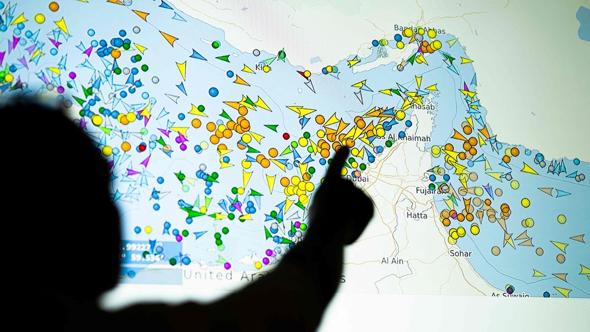 A photo illustration shows a person in front of a large screen displaying vessel movements in the Strait of Hormuz on a ship-tracking website, May 4, 2026. (AFP Photo) 