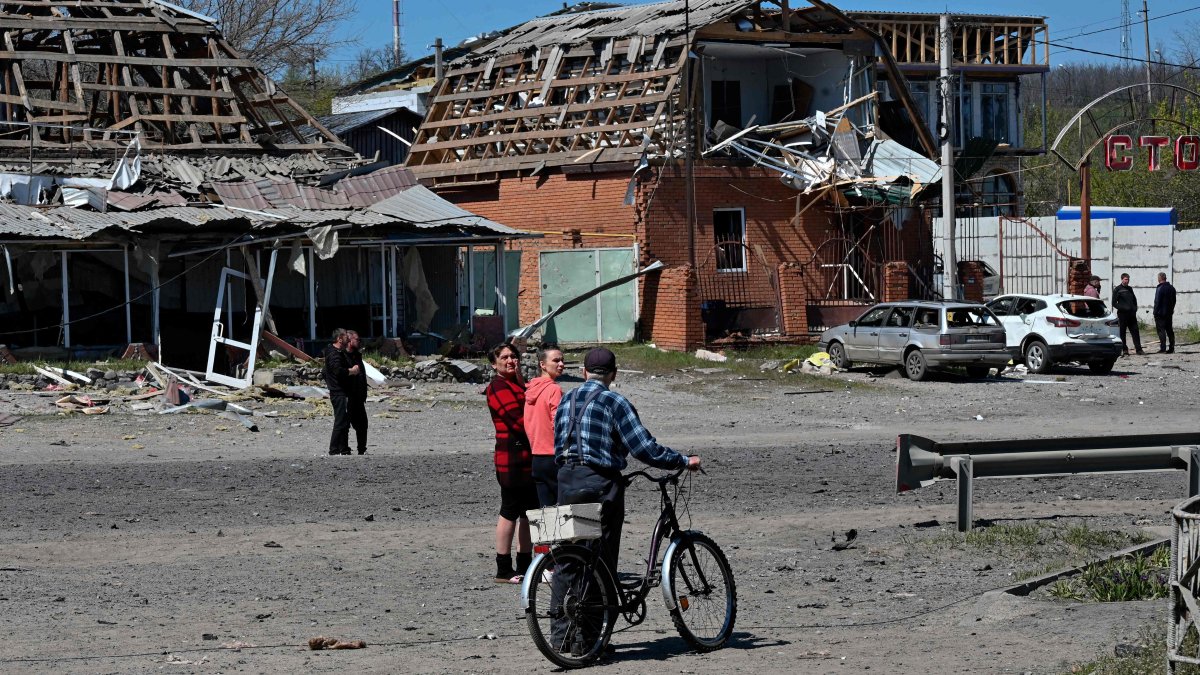 Residents walk past damaged buildings and cars at the site of a Russian missile strike in the town of Merefa, Kharkiv region, Ukraine, May 4, 2026. (AFP Photo)