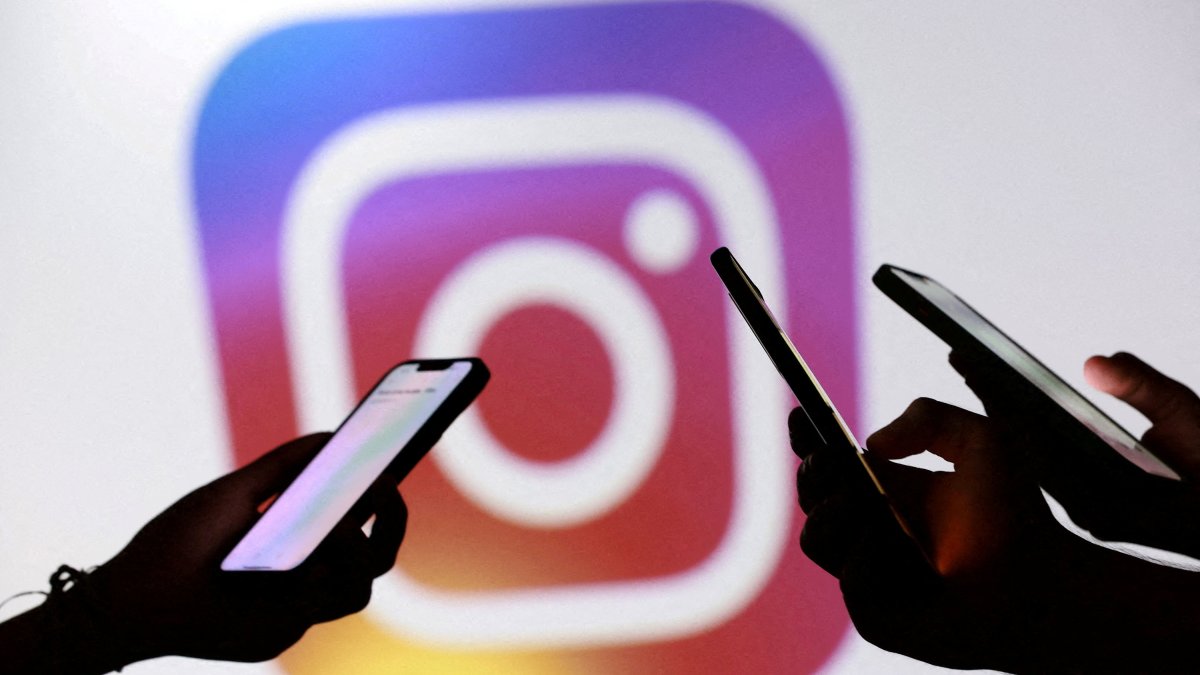 Teenagers pose for a photo while holding smartphones in front of a Facebook logo in this illustration, Sept. 11, 2025. (Reuters Photo)