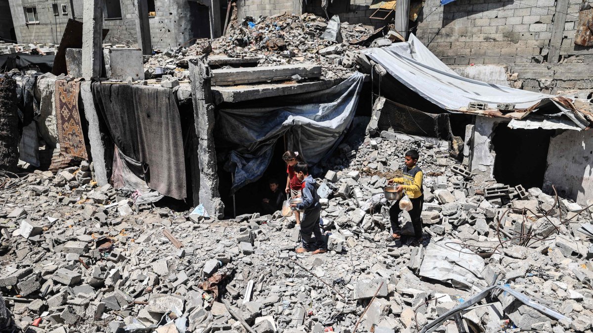 Displaced Palestinian children carry pots of food collected from a charity kitchen to their family shelter beneath the rubble of buildings destroyed by the Israeli military, in the Bureij refugee camp in the central Gaza Strip, May 1, 2026. (AFP Photo)