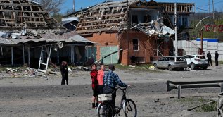 Residents walk past damaged buildings and cars at the site of a Russian missile strike in the town of Merefa, Kharkiv region, Ukraine, May 4, 2026. (AFP Photo)