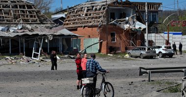 Residents walk past damaged buildings and cars at the site of a Russian missile strike in the town of Merefa, Kharkiv region, Ukraine, May 4, 2026. (AFP Photo)