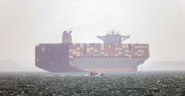 Iran-flagged container vessel Hamouna is pictured while anchored as a small motorboat passes by, in the Strait of Hormuz off Bandar Abbas in southern Iran, May 2, 2026. (AFP Photo)