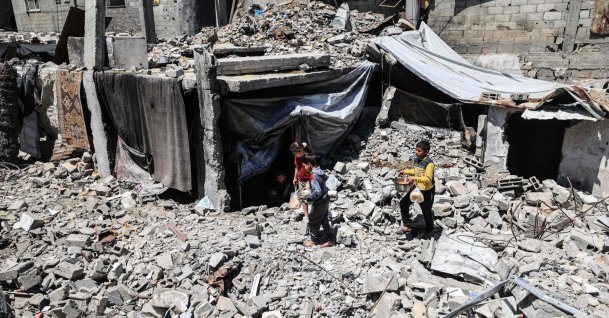 Displaced Palestinian children carry pots of food collected from a charity kitchen to their family shelter beneath the rubble of buildings destroyed by the Israeli military, in the Bureij refugee camp in the central Gaza Strip, May 1, 2026. (AFP Photo)