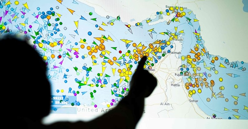 A photo illustration shows a person in front of a large screen displaying vessel movements in the Strait of Hormuz on a ship-tracking website, May 4, 2026. (AFP Photo) 