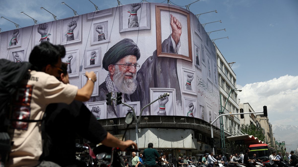People ride motorcycles near a billboard featuring an image of the late Supreme Leader of Iran, Ayatollah Ali Khamenei, in Tehran, Iran, May 6, 2026. (Reuters Photo)