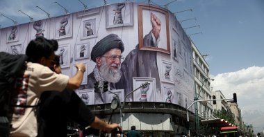 People ride motorcycles near a billboard featuring an image of the late Supreme Leader of Iran, Ayatollah Ali Khamenei, in Tehran, Iran, May 6, 2026. (Reuters Photo)