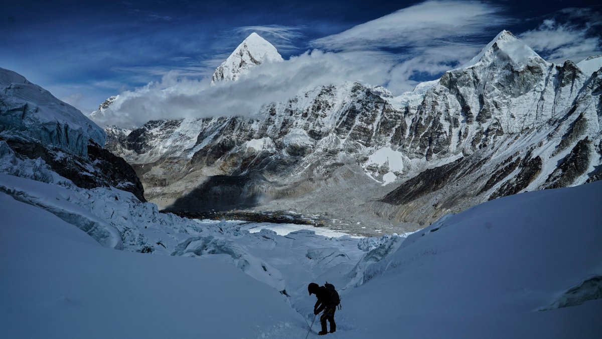 Mount Pumori, center left, looms in the background as a mountaineer negotiates Khumbu Icefall to descend to Everest Base Camp, Nepal, May 4, 2025. (AP Photo)