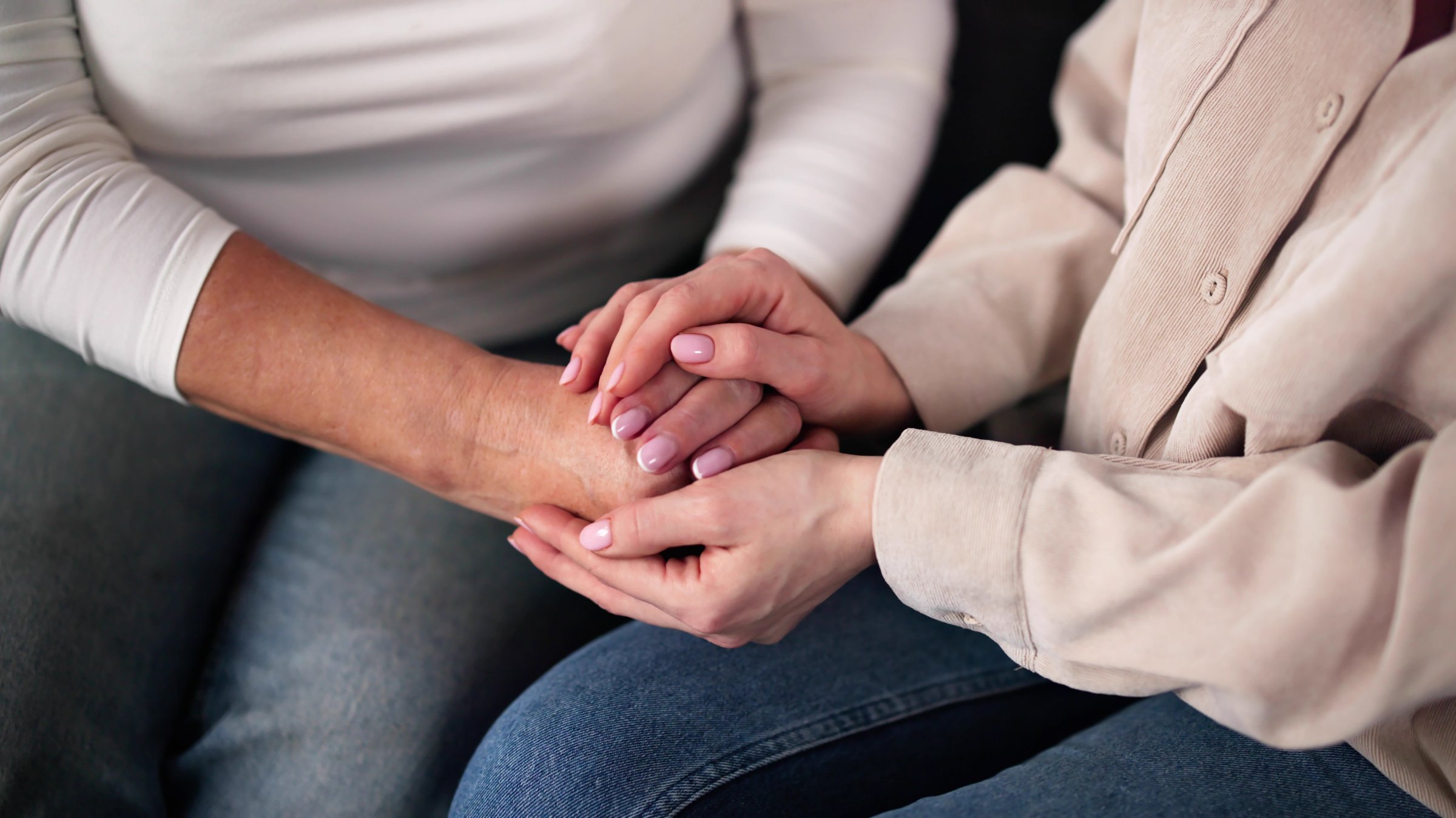 A woman holds an elderly family member’s hands while offering emotional support. (Shutterstock Photo) 