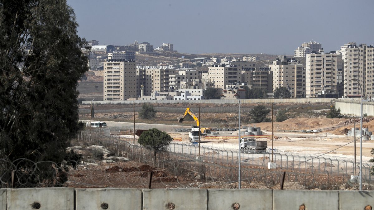A general view shows a section of Israel's controversial separation wall (bottom) and machinery working on the tarmac of the former Atarot airport (Jerusalem International Airport), which has been closed to civilian traffic since the breakout of the second Palestinian intifada (uprising) in 2000, near the village of Qalandia between the West Bank city of Ramallah and Israel-annexed east Jerusalem, Nov. 25, 2021. (AFP Photo)