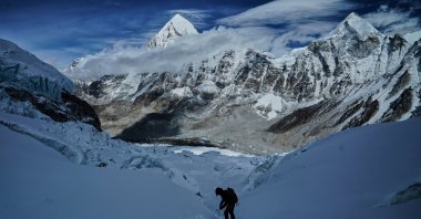 Mount Pumori, center left, looms in the background as a mountaineer negotiates Khumbu Icefall to descend to Everest Base Camp, Nepal, May 4, 2025. (AP Photo)